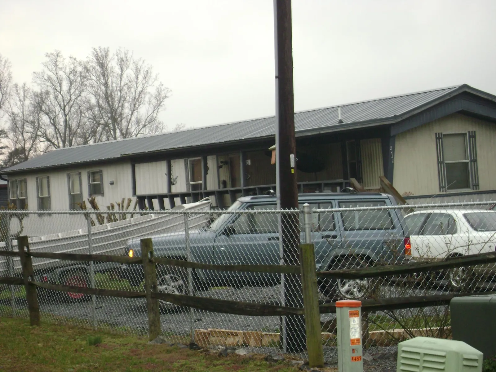 Dark metal roof on a long single story building behind a chain link fence in Pelham